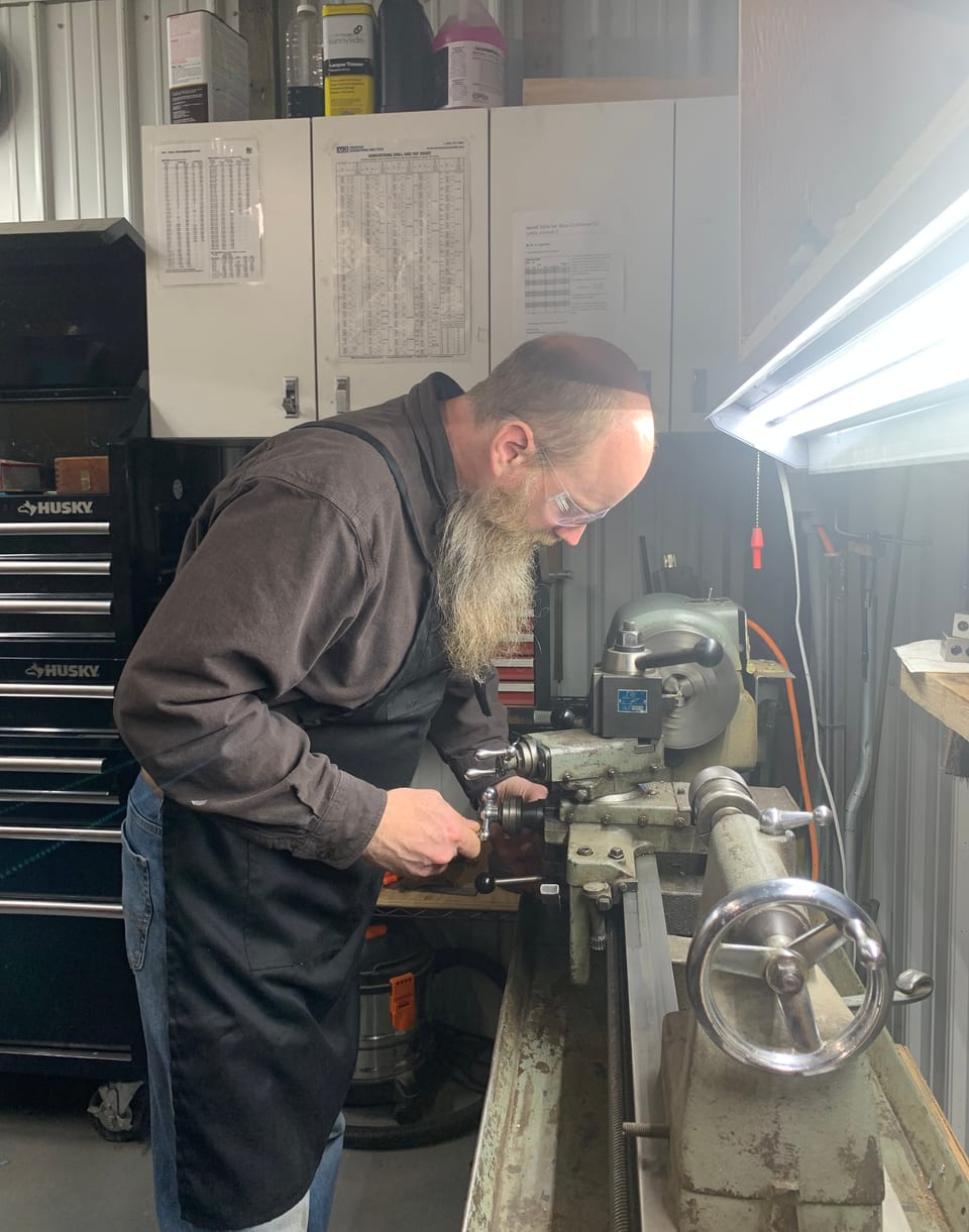 Ben at the milling machine in safety glasses, cutting on a firearm part.